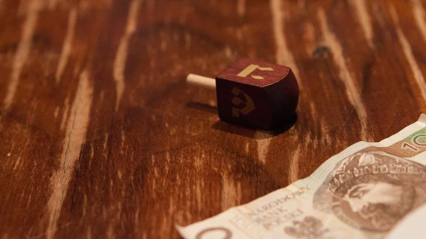 Drewniana kostka z symbolem na drewnianym stole obok banknotu polskich złotych